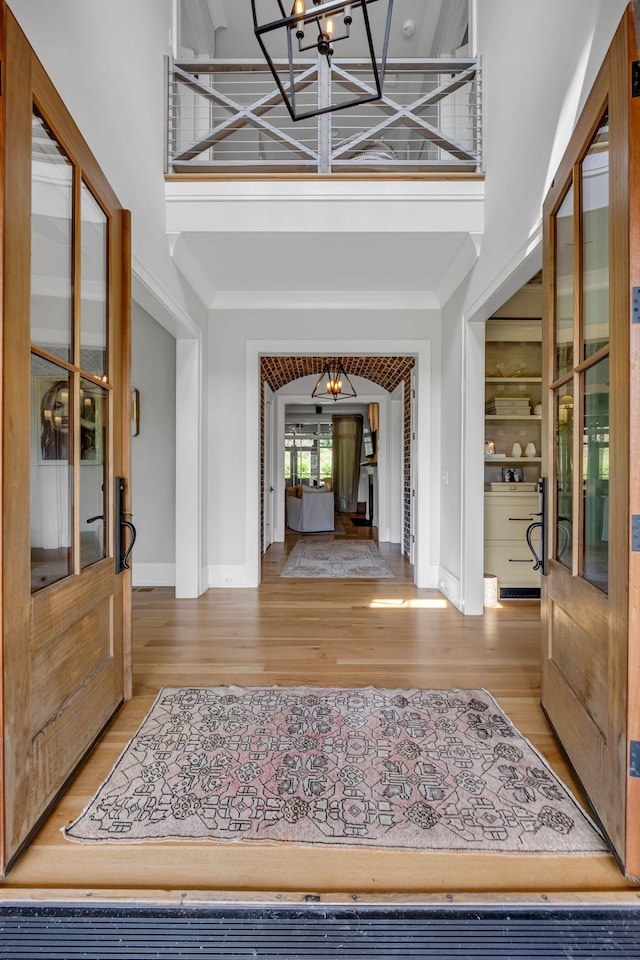 foyer entrance with a chandelier, french doors, a towering ceiling, and light hardwood / wood-style floors