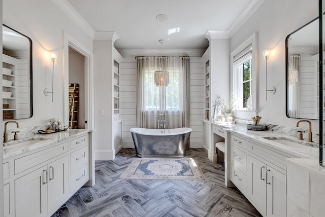 bathroom with parquet flooring, ornamental molding, vanity, and a bathing tub