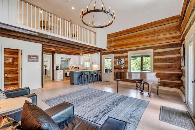 living room featuring a notable chandelier, sink, a high ceiling, and light hardwood / wood-style flooring