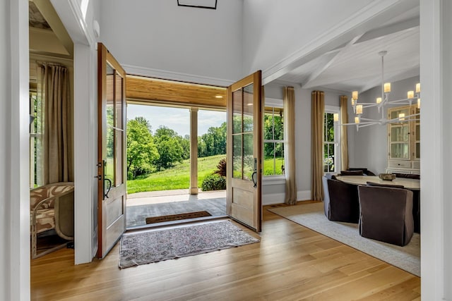 doorway with a chandelier, light hardwood / wood-style floors, and vaulted ceiling