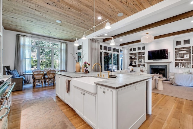 kitchen with wooden ceiling, a kitchen island with sink, white cabinets, built in shelves, and decorative light fixtures