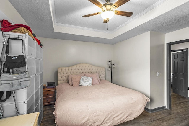 bedroom featuring a textured ceiling, ornamental molding, dark hardwood / wood-style floors, a raised ceiling, and ceiling fan