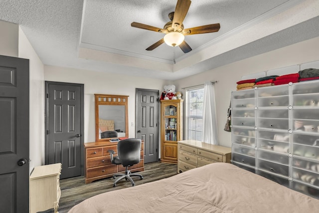 bedroom featuring dark hardwood / wood-style flooring, a textured ceiling, a raised ceiling, and ceiling fan