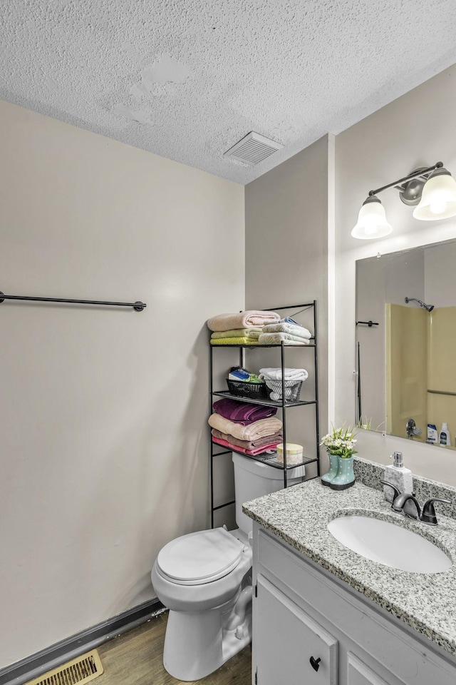 bathroom featuring vanity, wood-type flooring, a textured ceiling, a shower, and toilet