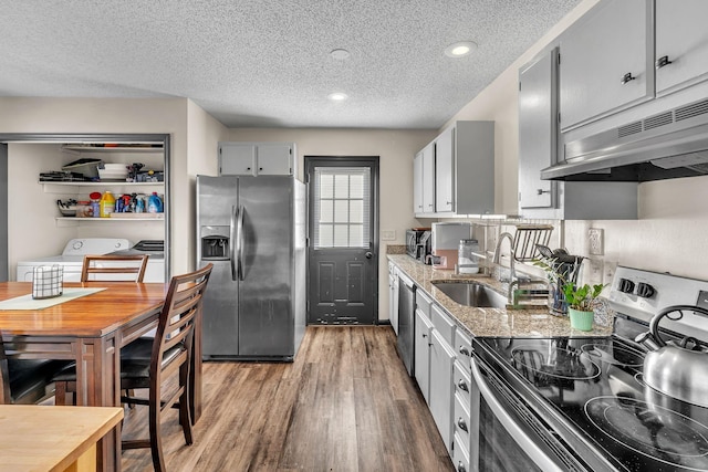 kitchen with gray cabinetry, stainless steel appliances, independent washer and dryer, wood-type flooring, and a textured ceiling