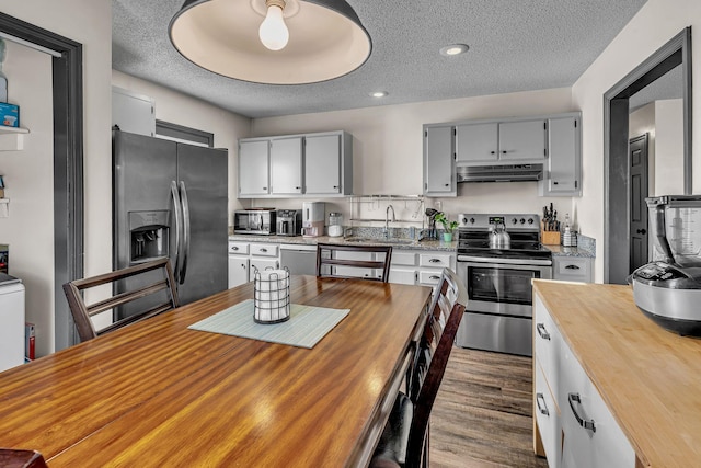 kitchen featuring appliances with stainless steel finishes, sink, a textured ceiling, and dark hardwood / wood-style floors