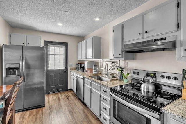 kitchen featuring hardwood / wood-style floors, stainless steel appliances, sink, and a textured ceiling