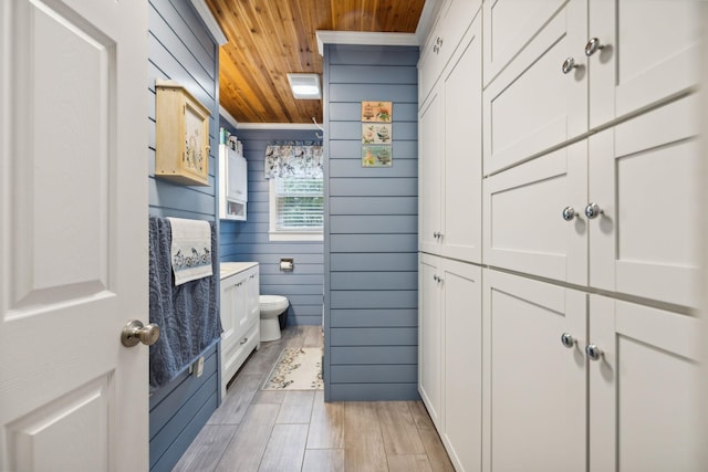 bathroom featuring ornamental molding, wood ceiling, vanity, wooden walls, and toilet