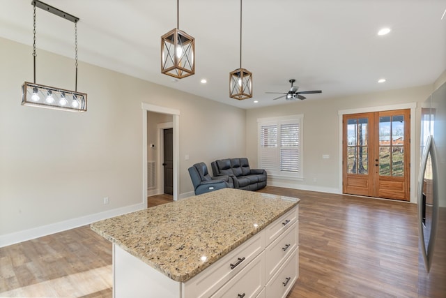 kitchen with ceiling fan, a center island, white cabinetry, and hanging light fixtures