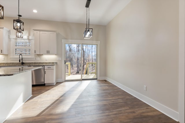 kitchen featuring white cabinets, dishwasher, pendant lighting, and dark stone counters