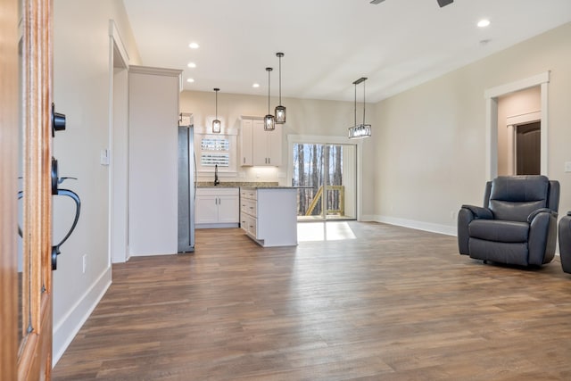 kitchen featuring hardwood / wood-style flooring, decorative light fixtures, white cabinetry, and stainless steel refrigerator