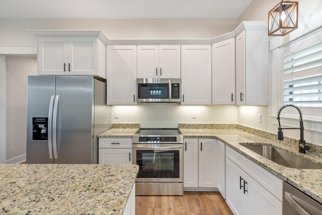 kitchen with white cabinets, stainless steel appliances, hanging light fixtures, and sink