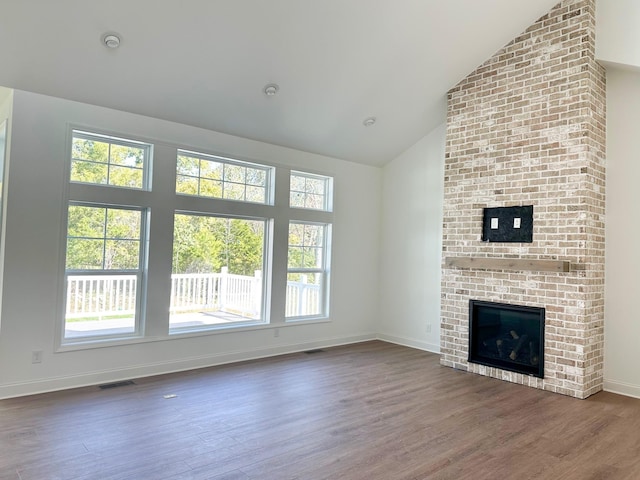 unfurnished living room featuring a fireplace, dark hardwood / wood-style floors, and high vaulted ceiling