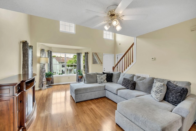 living room featuring a textured ceiling, light hardwood / wood-style floors, and ceiling fan