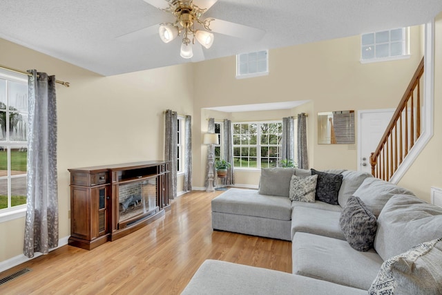 living room featuring ceiling fan, light hardwood / wood-style floors, and a textured ceiling