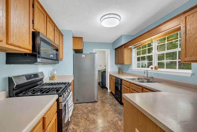 kitchen featuring washer / dryer, sink, a textured ceiling, and appliances with stainless steel finishes