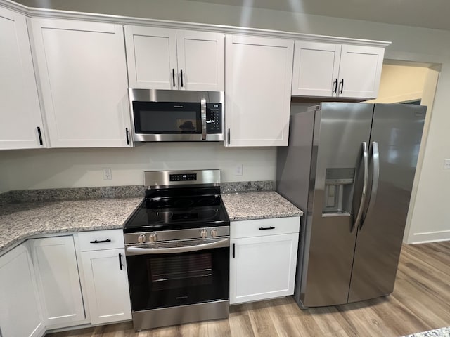 kitchen with white cabinets, stainless steel appliances, and light hardwood / wood-style flooring