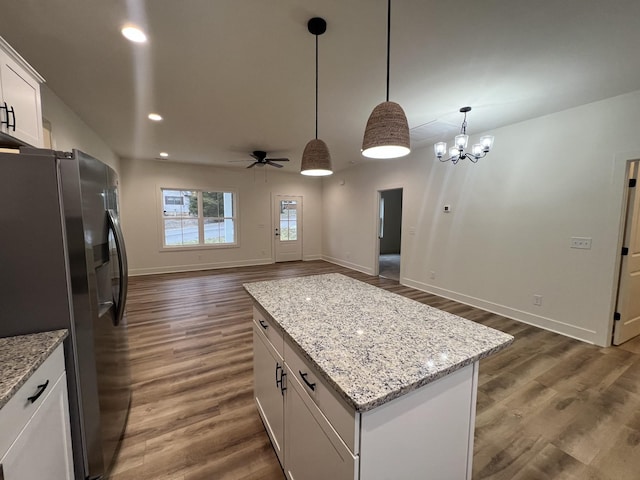 kitchen with white cabinets, ceiling fan with notable chandelier, stainless steel refrigerator with ice dispenser, decorative light fixtures, and a kitchen island