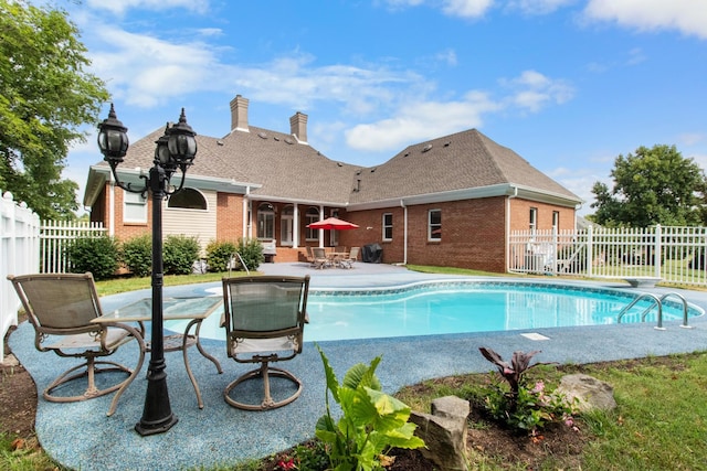 view of swimming pool featuring a patio and a diving board