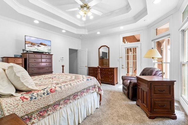 bedroom featuring ornamental molding, light colored carpet, ceiling fan, and a tray ceiling