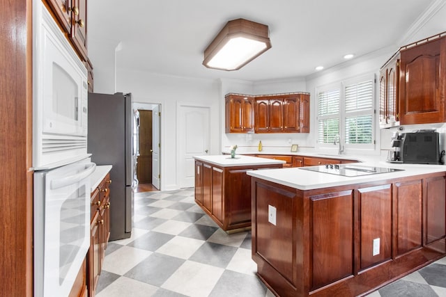 kitchen with kitchen peninsula, black electric cooktop, sink, a kitchen island, and stainless steel refrigerator