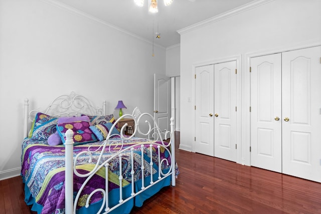 bedroom featuring ornamental molding, dark wood-type flooring, and multiple closets