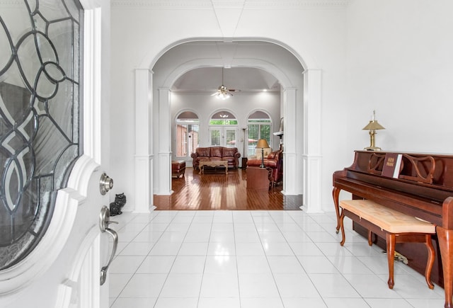 tiled foyer with ceiling fan and crown molding