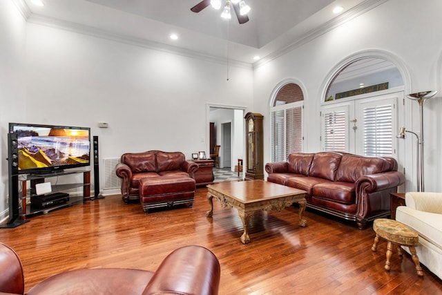 living room featuring wood-type flooring, a towering ceiling, and ceiling fan