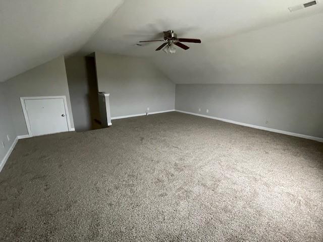 additional living space featuring vaulted ceiling, ceiling fan, and dark colored carpet