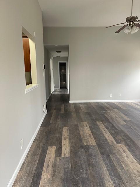 empty room with ceiling fan and dark wood-type flooring