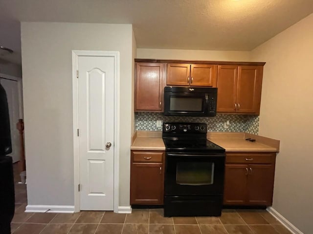 kitchen featuring dark tile patterned floors, tasteful backsplash, and black appliances