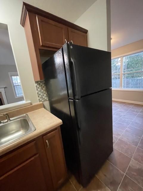 kitchen with black refrigerator, tile patterned floors, and sink