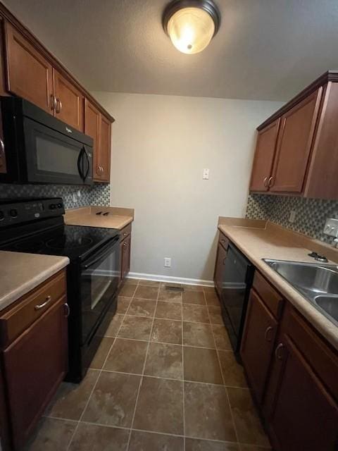 kitchen featuring sink, dark tile patterned flooring, black appliances, and tasteful backsplash