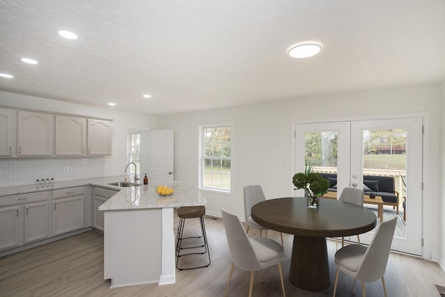 kitchen featuring light stone countertops, french doors, plenty of natural light, and sink