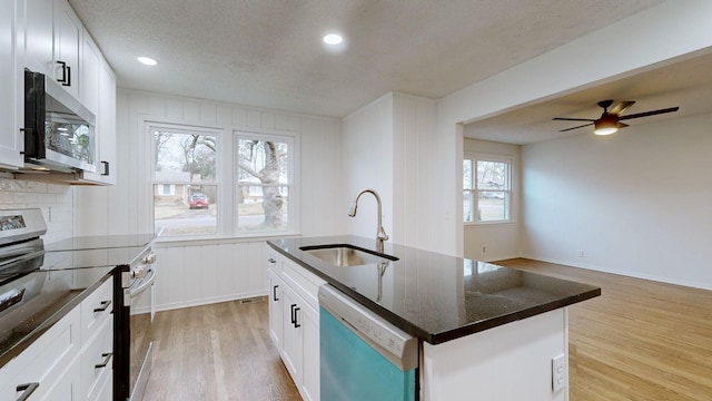 kitchen featuring stainless steel appliances, white cabinetry, a center island with sink, and sink