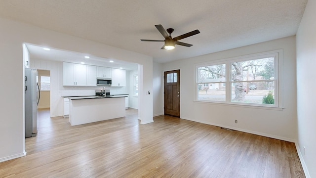 unfurnished living room with ceiling fan, light hardwood / wood-style floors, and sink