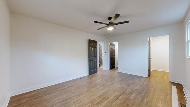 unfurnished bedroom featuring a walk in closet, light hardwood / wood-style flooring, and ceiling fan