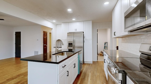 kitchen featuring a center island, sink, light hardwood / wood-style floors, white cabinetry, and stainless steel appliances