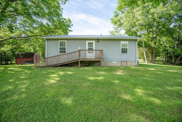 rear view of property with a storage unit, a yard, and a wooden deck