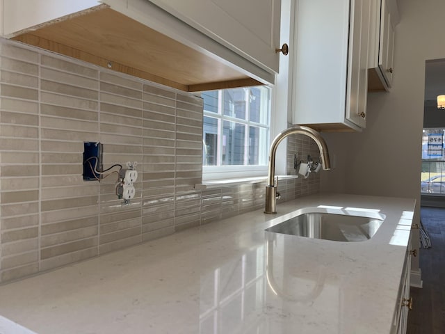 details with tasteful backsplash, a sink, and light stone countertops