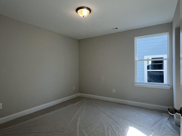 carpeted spare room featuring visible vents and baseboards