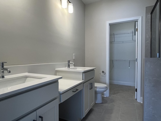 bathroom featuring toilet, tile patterned flooring, a walk in closet, and vanity