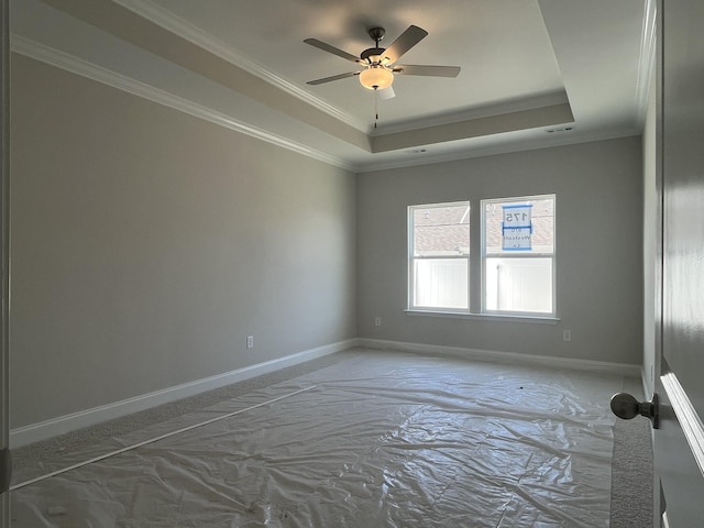 unfurnished room with crown molding, a tray ceiling, a ceiling fan, and baseboards