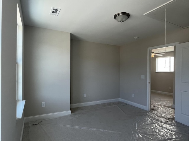 unfurnished room featuring attic access, visible vents, and baseboards