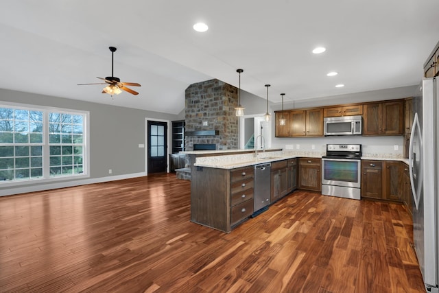 kitchen with lofted ceiling, ceiling fan, light stone counters, dark hardwood / wood-style flooring, and stainless steel appliances