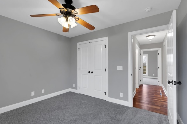 unfurnished bedroom featuring ceiling fan, dark carpet, and a closet