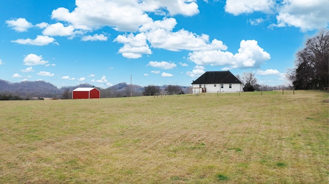 view of yard featuring a mountain view, a rural view, and an outbuilding