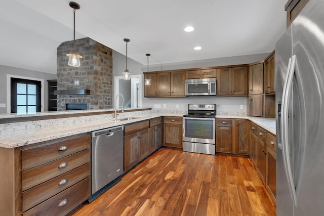 kitchen with sink, decorative light fixtures, light stone counters, kitchen peninsula, and stainless steel appliances