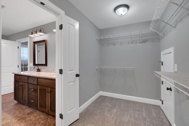 spacious closet with light colored carpet and sink