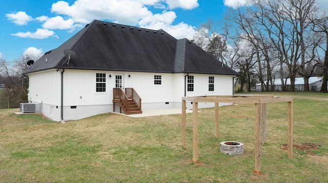 rear view of property featuring central air condition unit, a lawn, and an outdoor fire pit